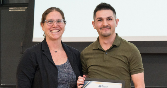 Administrator on stage with a student receiving a framed award on stage